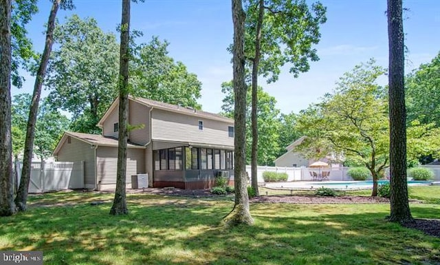 back of house with a fenced in pool, a sunroom, a lawn, and fence