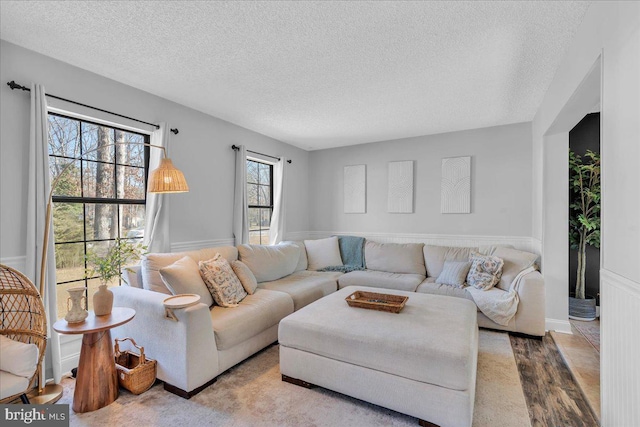 living room featuring light wood-style floors, a wainscoted wall, and a textured ceiling