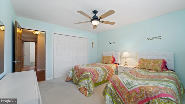 bedroom with a closet, light carpet, ceiling fan, and baseboards