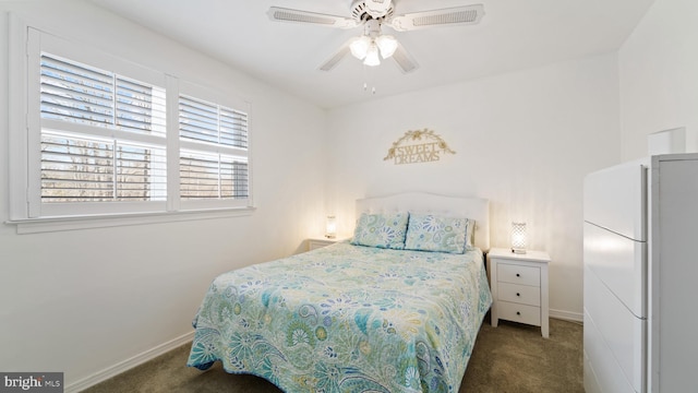 bedroom with baseboards, dark carpet, a ceiling fan, and freestanding refrigerator