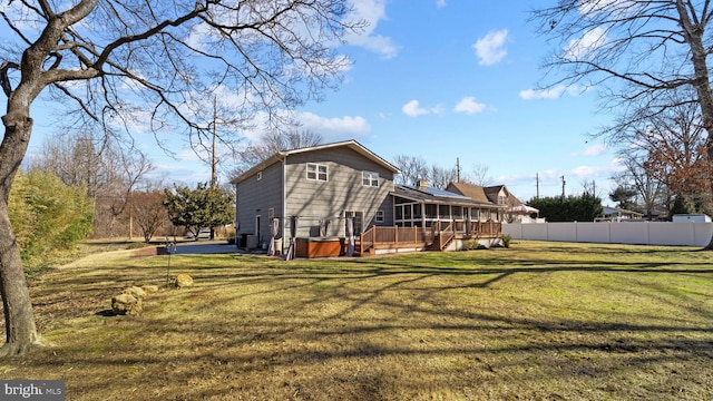 back of property featuring a yard, fence, a sunroom, and a hot tub