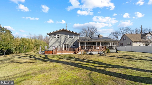 rear view of property featuring a hot tub, a sunroom, roof mounted solar panels, fence, and a deck