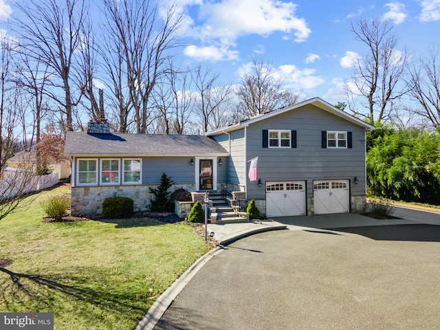 split level home featuring a garage, driveway, a front lawn, and stone siding