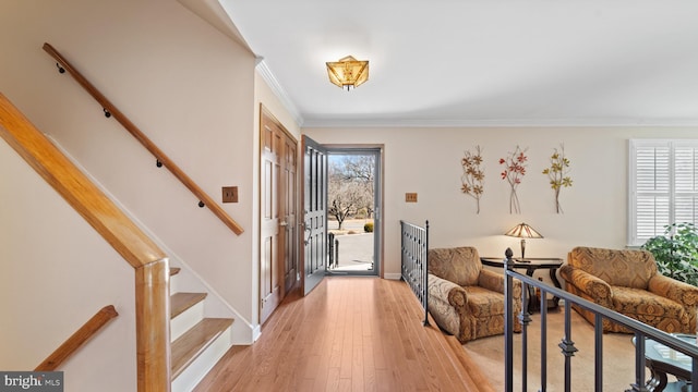 entryway with light wood-style flooring, stairway, and crown molding