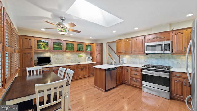 kitchen featuring brown cabinetry, a skylight, appliances with stainless steel finishes, and light countertops