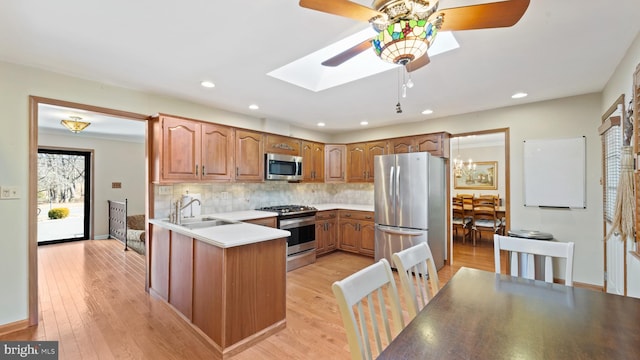 kitchen with stainless steel appliances, tasteful backsplash, light countertops, light wood-style floors, and a sink