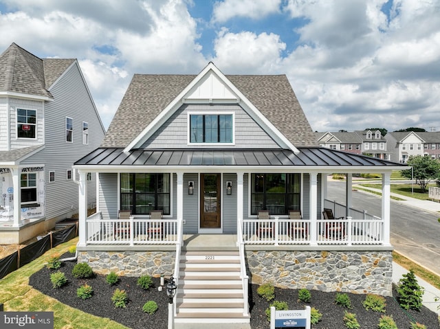 view of front facade featuring metal roof, roof with shingles, a porch, and a standing seam roof