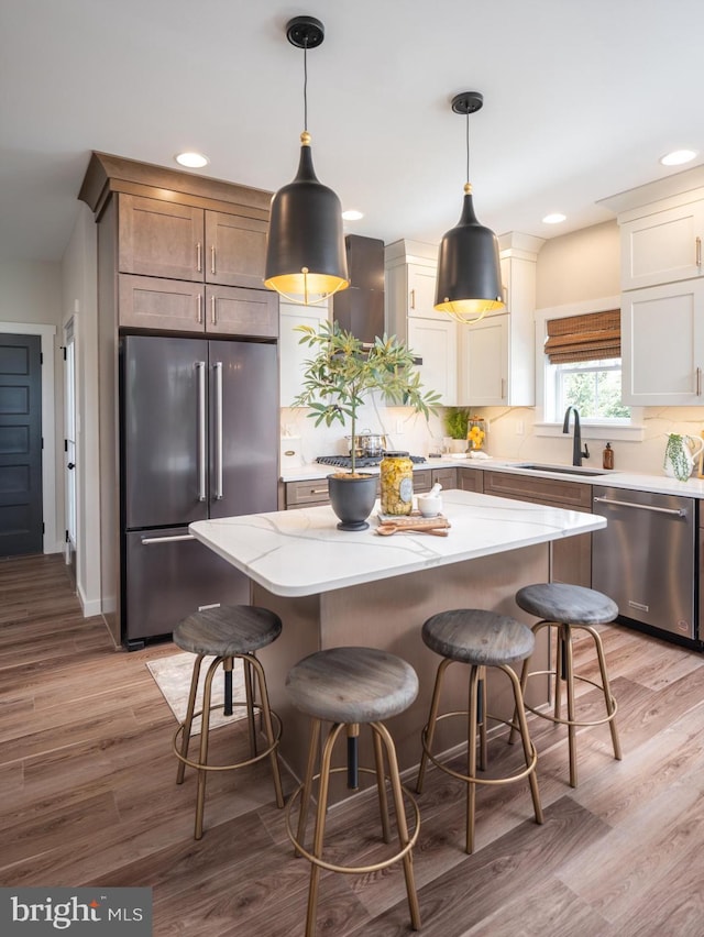 kitchen with stainless steel appliances, a center island, pendant lighting, and a sink