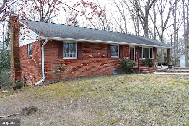 ranch-style home with a front yard, a shingled roof, a chimney, and brick siding