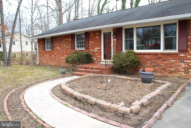 ranch-style home featuring brick siding, a chimney, and roof with shingles