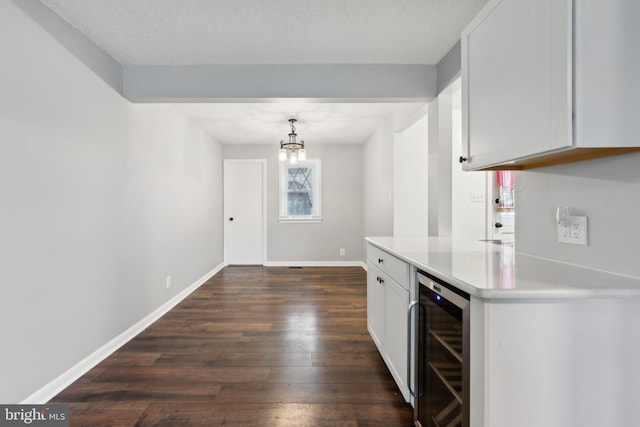 kitchen with beverage cooler, white cabinets, light countertops, dark wood finished floors, and pendant lighting