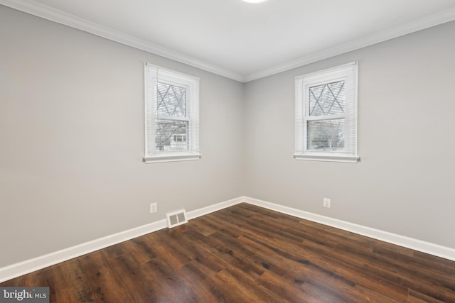 spare room featuring baseboards, visible vents, dark wood-type flooring, and ornamental molding