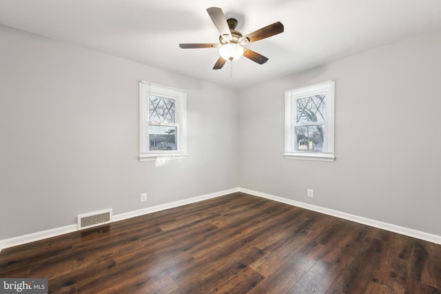 unfurnished room featuring dark wood-style floors, visible vents, plenty of natural light, and baseboards