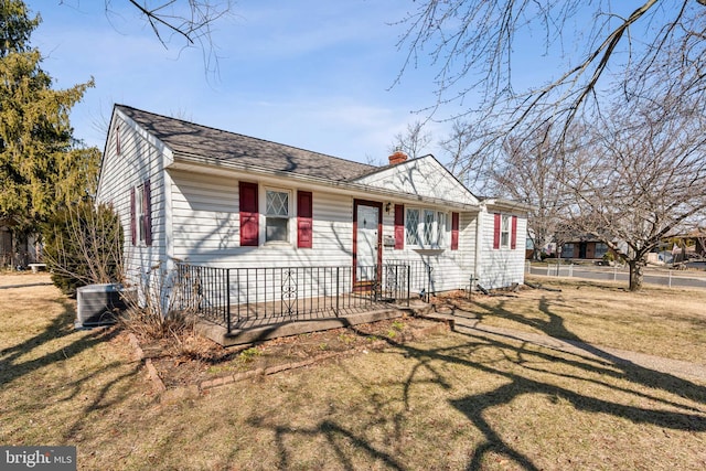 view of front of home with central AC, a front lawn, and fence