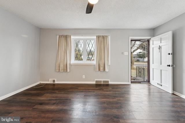 empty room with visible vents, dark wood finished floors, and a wealth of natural light