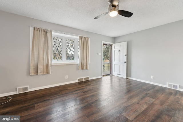 spare room featuring baseboards, visible vents, and dark wood finished floors