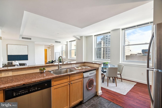 kitchen with washer / clothes dryer, visible vents, appliances with stainless steel finishes, open floor plan, and a sink