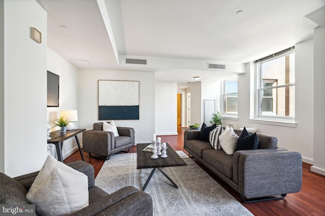 living room featuring dark wood-style floors, visible vents, and baseboards