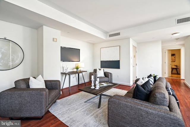 living area with dark wood-type flooring, visible vents, and baseboards