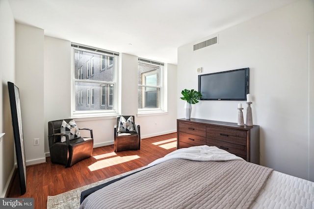 bedroom with dark wood-style floors, visible vents, and baseboards