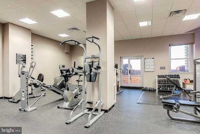 exercise room featuring a drop ceiling, visible vents, and baseboards