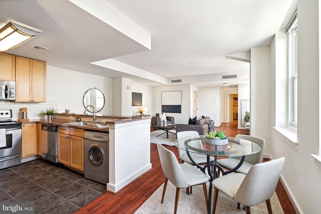 kitchen featuring washer / dryer, visible vents, dark countertops, appliances with stainless steel finishes, and open floor plan