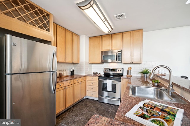 kitchen featuring appliances with stainless steel finishes, decorative backsplash, a sink, and light brown cabinetry