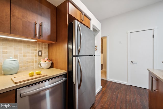 kitchen with stainless steel appliances, light countertops, tasteful backsplash, brown cabinetry, and dark wood finished floors