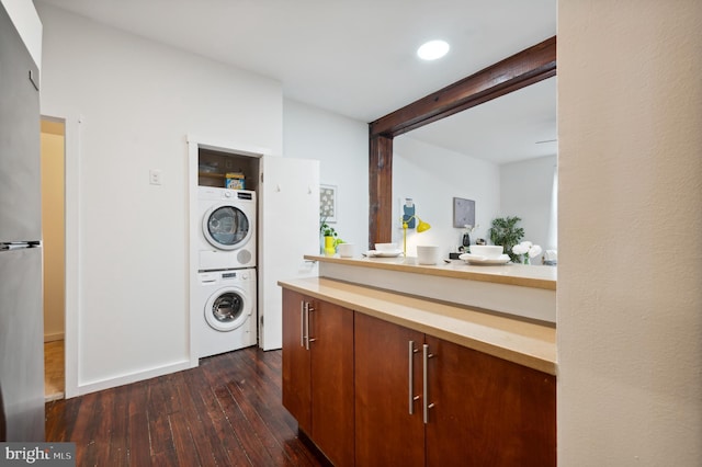 washroom featuring stacked washer and clothes dryer, dark wood finished floors, and laundry area