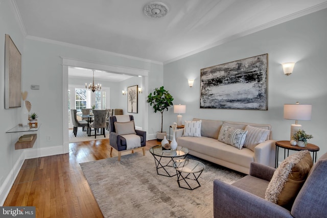 living area featuring a chandelier, crown molding, baseboards, and hardwood / wood-style flooring