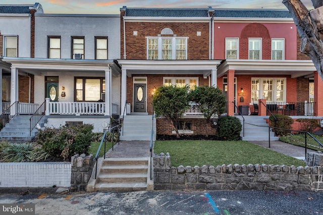 multi unit property featuring a yard, a porch, and brick siding