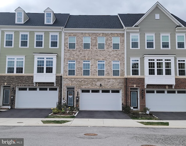 view of property featuring driveway, an attached garage, and brick siding