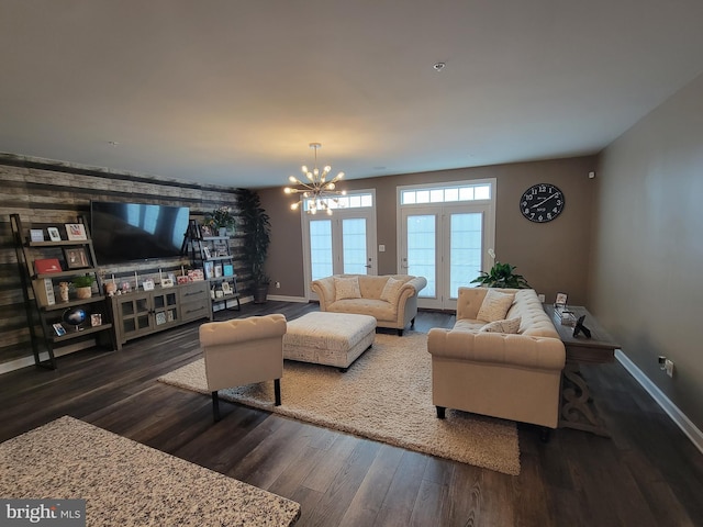 living area featuring dark wood-type flooring, a notable chandelier, and baseboards