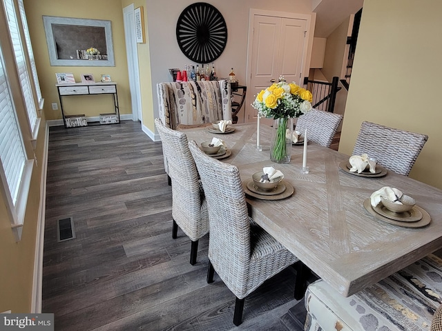 dining area with dark wood-style floors, visible vents, and baseboards