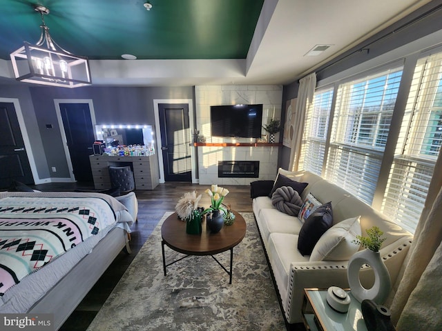 interior space featuring baseboards, visible vents, a tile fireplace, dark wood-style floors, and a notable chandelier