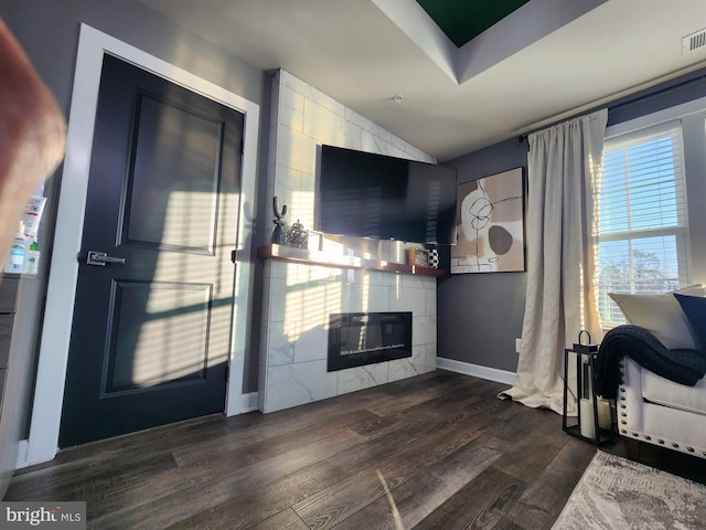 entryway featuring dark wood-style floors, a tile fireplace, visible vents, and baseboards