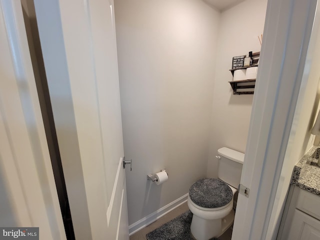 bathroom featuring baseboards, vanity, and toilet