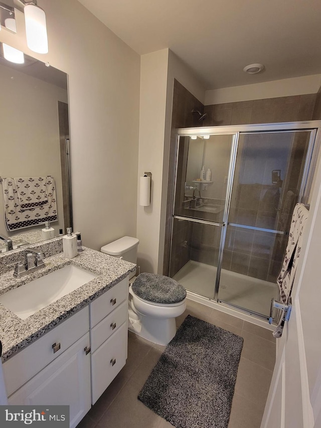 bathroom with tile patterned flooring, a shower stall, toilet, and vanity