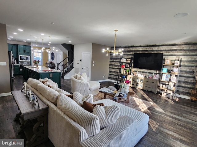 living area featuring stairs, an accent wall, dark wood-type flooring, and recessed lighting