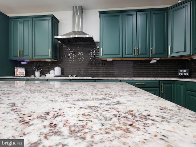 kitchen with decorative backsplash, black electric stovetop, green cabinetry, and wall chimney exhaust hood