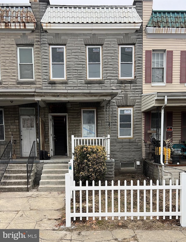 multi unit property with stone siding, a fenced front yard, and a tile roof