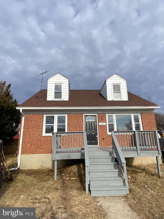 view of front of house featuring brick siding and roof with shingles