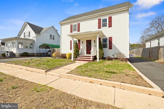 view of front of property with a front yard, driveway, and fence