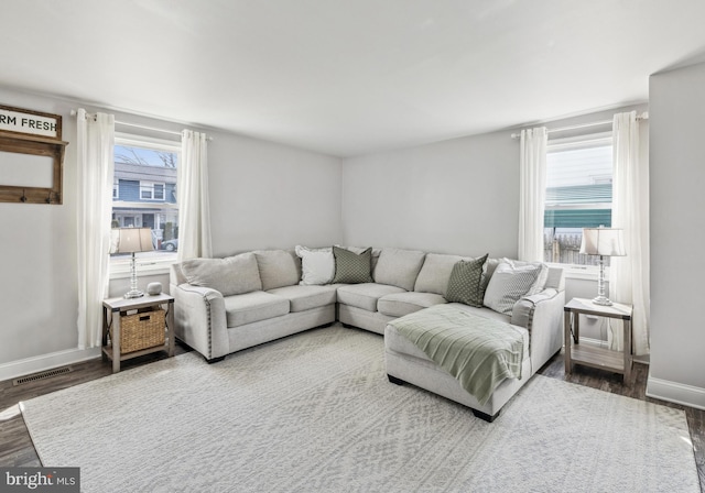 living area featuring a wealth of natural light, visible vents, baseboards, and wood finished floors