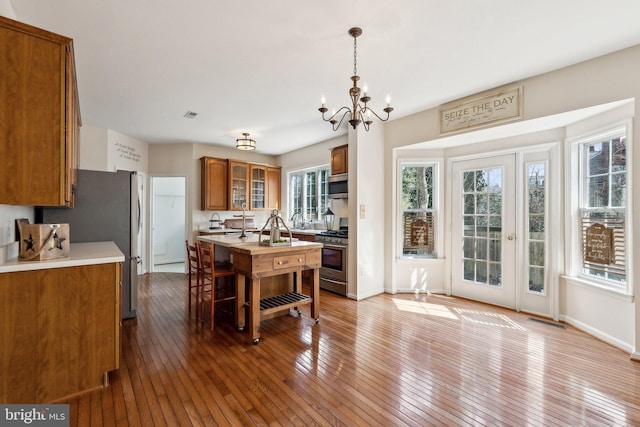 kitchen featuring brown cabinets, light countertops, visible vents, gas range, and hardwood / wood-style flooring