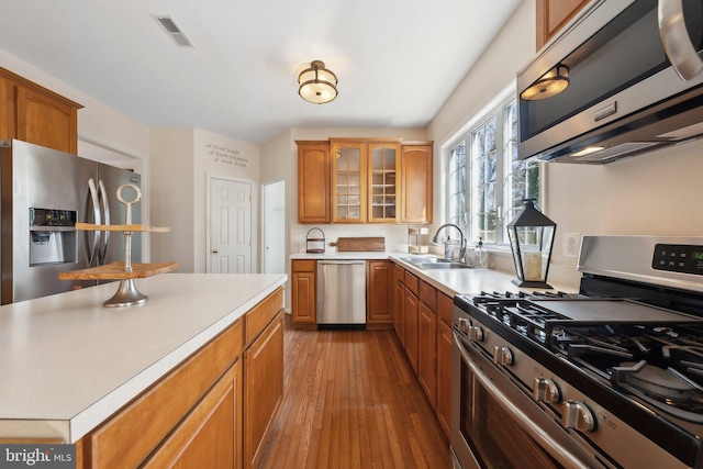 kitchen with dark wood-style flooring, light countertops, visible vents, appliances with stainless steel finishes, and glass insert cabinets