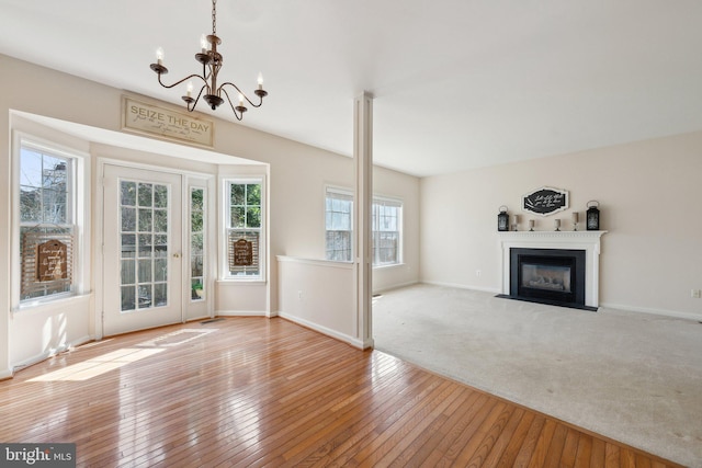 interior space with a notable chandelier, a fireplace with flush hearth, carpet flooring, baseboards, and hardwood / wood-style flooring