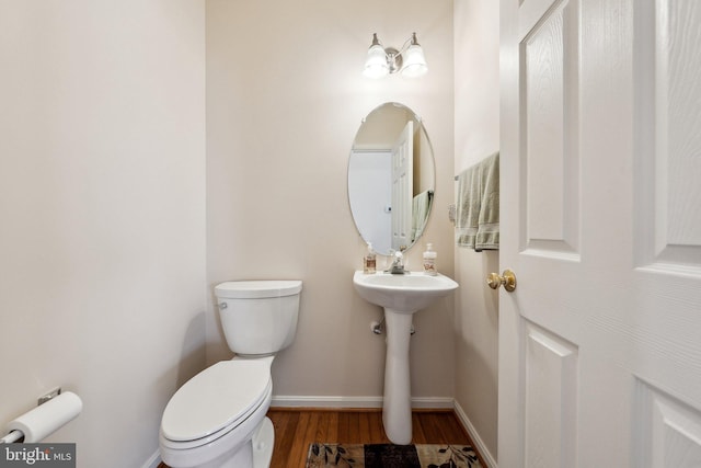 half bath featuring baseboards, toilet, and wood finished floors