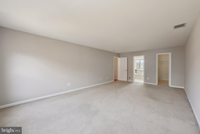 unfurnished bedroom with light carpet, visible vents, baseboards, a spacious closet, and a closet