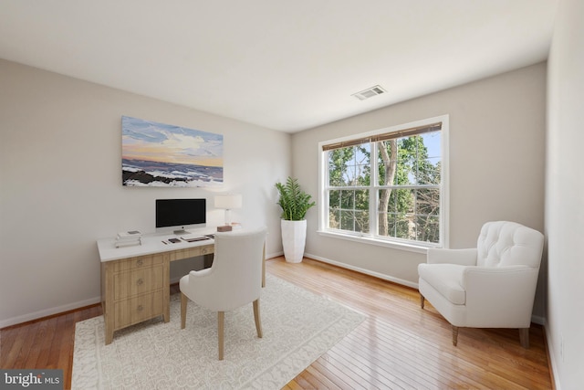 home office featuring light wood-type flooring, visible vents, and baseboards